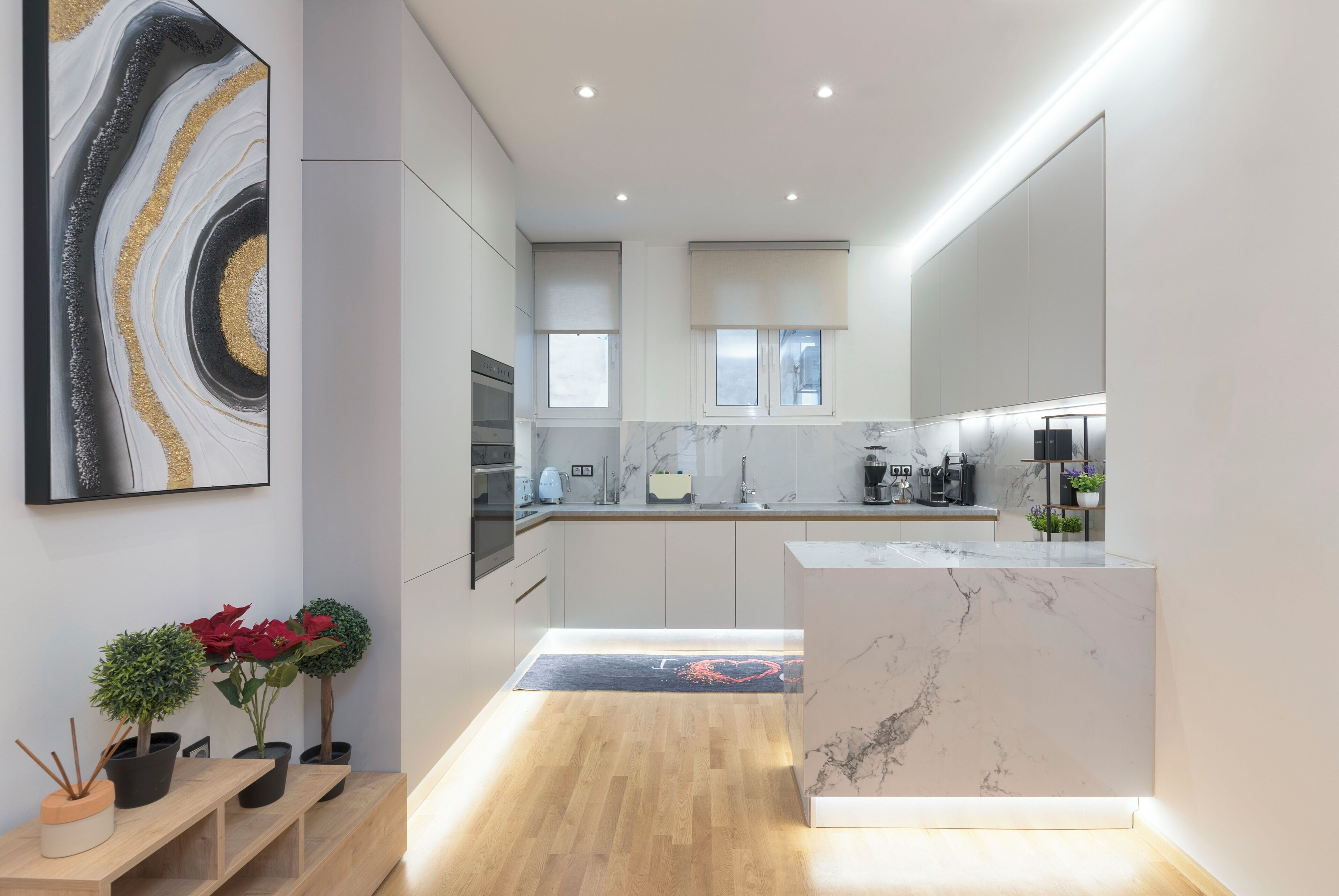 Una cocina moderna con encimeras de mármol, electrodomésticos integrados y una isla central.
