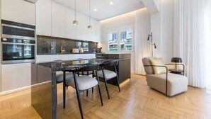 A modern kitchen with a marble countertop, stainless steel appliances, and pendant lighting. - Michalakopoulou Corner & Bright Apartment, Luxury (Athens)
