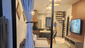 Un salon moderne avec un canapé, un téléviseur et un escalier menant à un niveau supérieur.