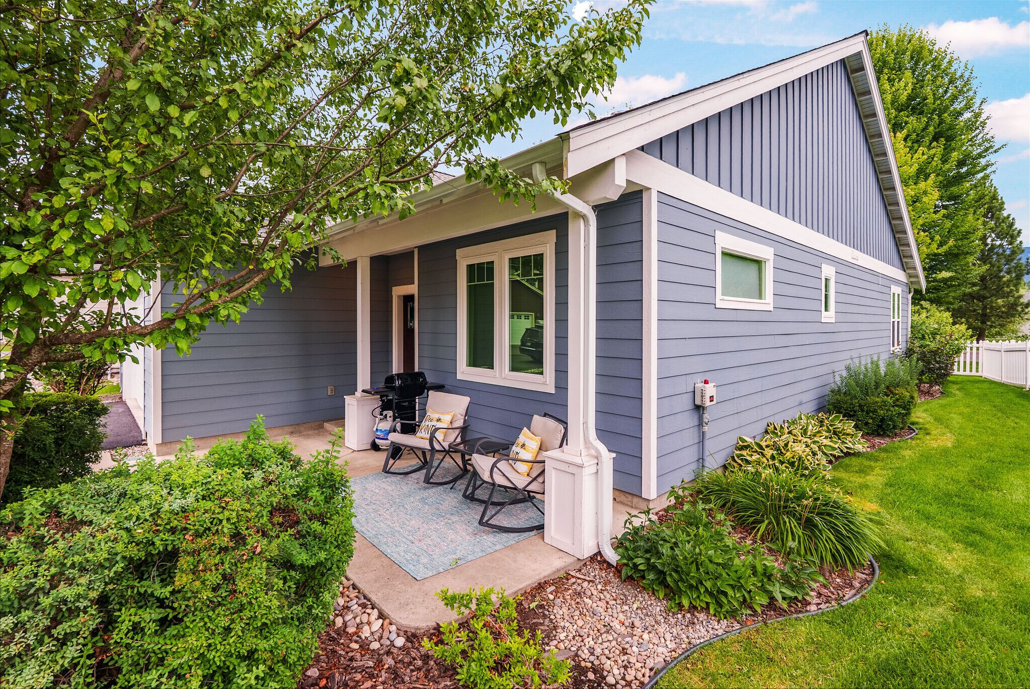 A house with a covered porch, a grill, and outdoor seating.