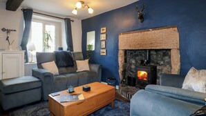 A cozy living room with a stone fireplace, a sofa, a coffee table, and a blue accent wall.