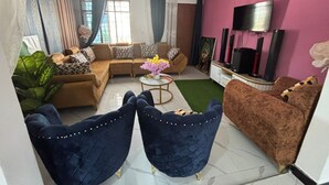 A living room with a sofa set, two armchairs, a coffee table, and a TV.