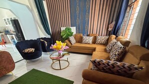 A living room with a brown sofa, a black armchair, and a green rug.