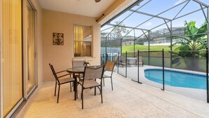 A covered patio with a pool, a ceiling fan, and a table with chairs. - Davenport Luxury 8-Guest Villa (Davenport)