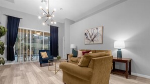 A modern living room with a sofa, armchair, and a glass partition. - Davenport Luxury 8-Guest Villa (Davenport)