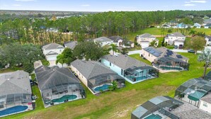 A residential area with multiple houses, some with large glass-enclosed swimming pools, surrounded by greenery and trees. - Davenport Luxury 8-Guest Villa (Davenport)