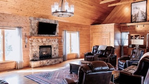 A log cabin interior with a stone fireplace, leather recliners, and a chandelier. - Mirror Lake - Rare private lake! (Scales Mound)