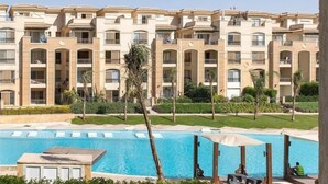 A multi-story hotel with a swimming pool, outdoor seating, and palm trees. - Kennah Milena | Stone Residence, New Cairo - Families Only (New Cairo)