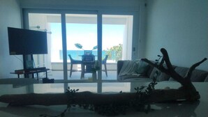 Ein modernes Wohnzimmer mit einem Glastisch, einer Couch und einem Fernseher auf einem Schrank.