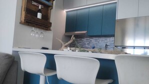 Eine moderne Küche mit blauen Schränken, einer weißen Arbeitsplatte und drei weißen Barhocker.