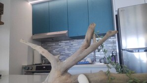 Eine Küche mit blauen Schränken, einem Edelstahlkühlschrank und einem dekorativen Holzast.