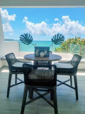 A round table with two chairs, a decorative box with sea creatures, and a view of the ocean.