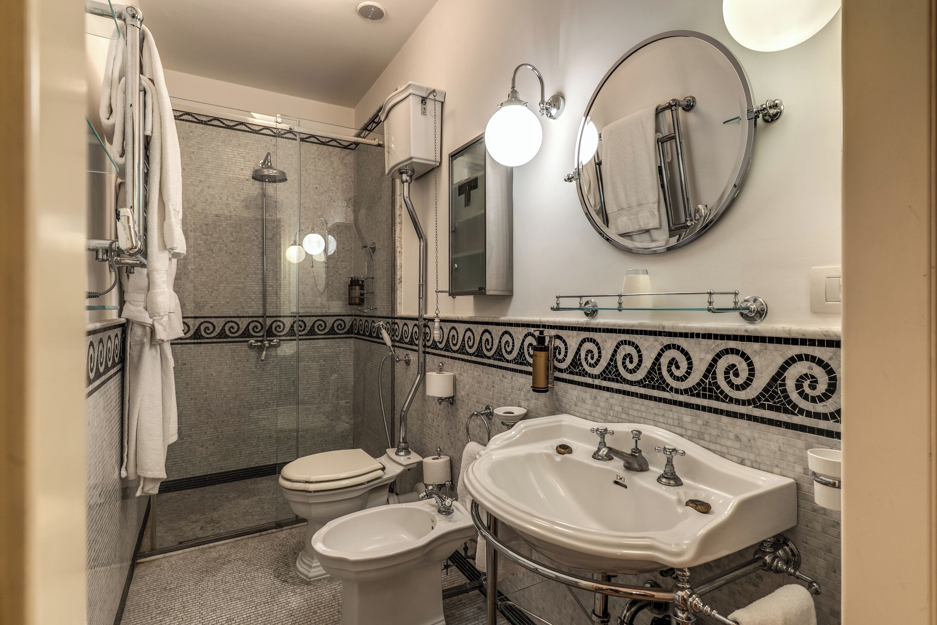 A bathroom with a shower, toilet, bidet, and sink.
