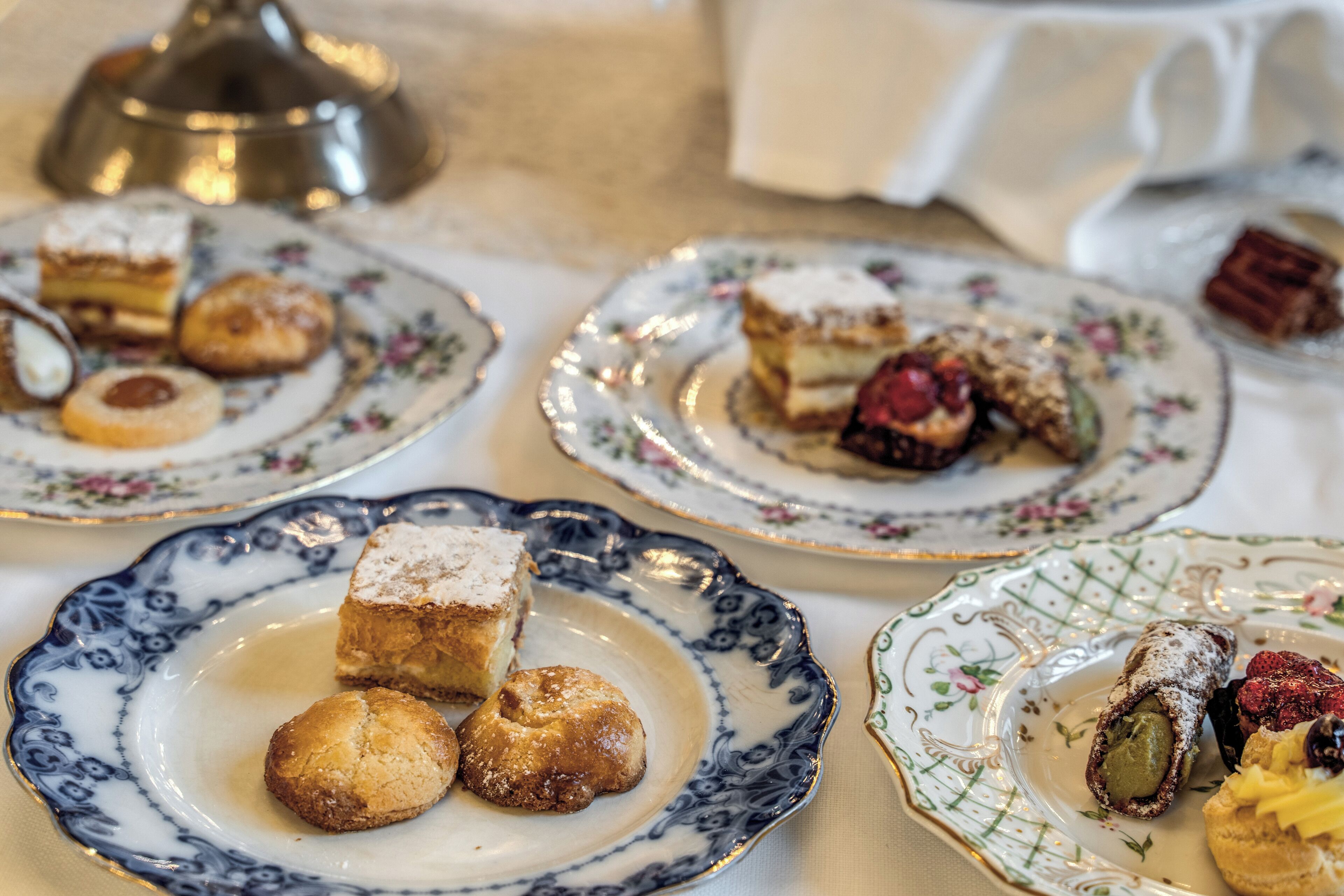 A table with various pastries and desserts on ornate plates.