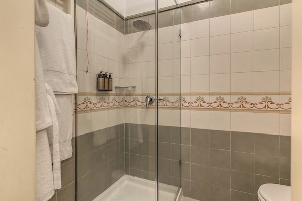 A shower area with a glass door, a white bathtub, and a toilet visible in the corner. - Palazzo Doria Suites (Naples)