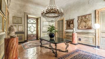 A grand room with a chandelier, a marble table, and classical artwork.