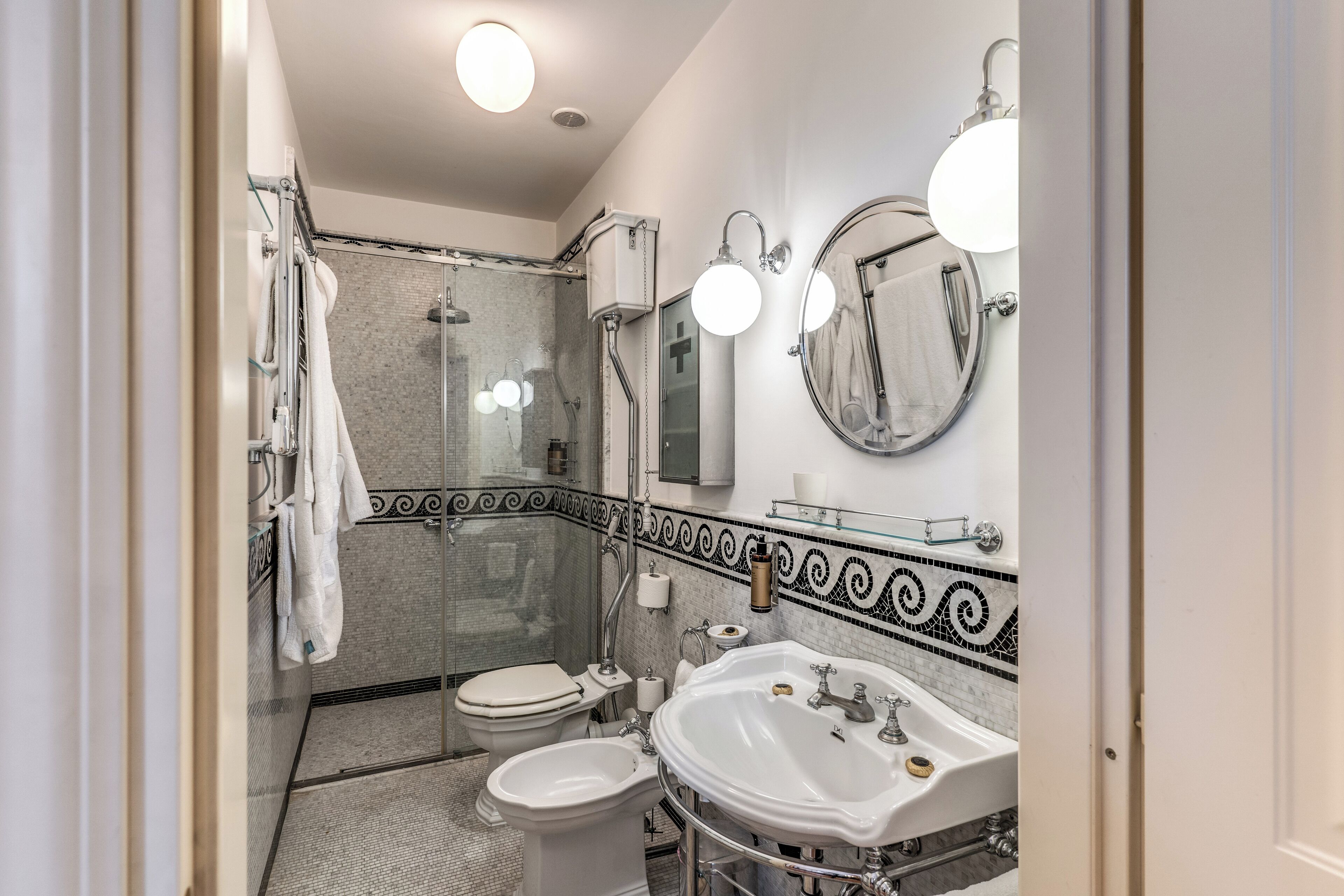 A modern bathroom with a shower, toilet, bidet, and a large sink.