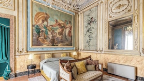 A luxurious bedroom with a large mural, a bed, a sofa, and a radiator. - Palazzo Doria Suites (Naples)