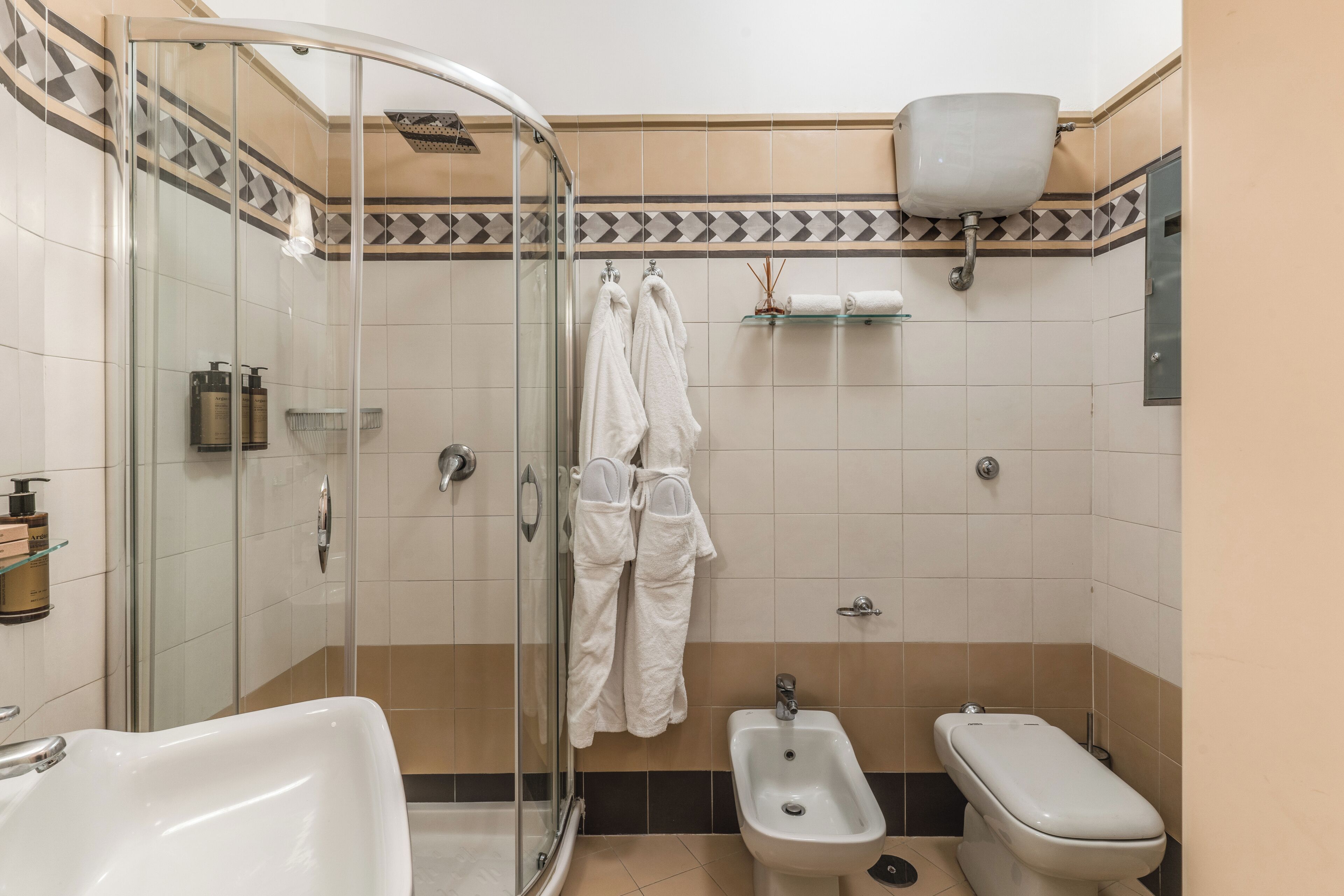 A bathroom with a glass-enclosed shower, a bidet, a toilet, and a sink.