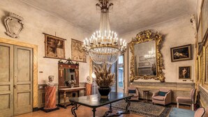 A grand room with a chandelier, a marble bust, and a large mirror. - Palazzo Doria Suites (Naples)