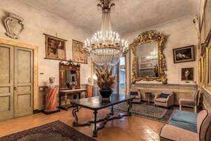 A grand room with a chandelier, a marble bust, and a large mirror.