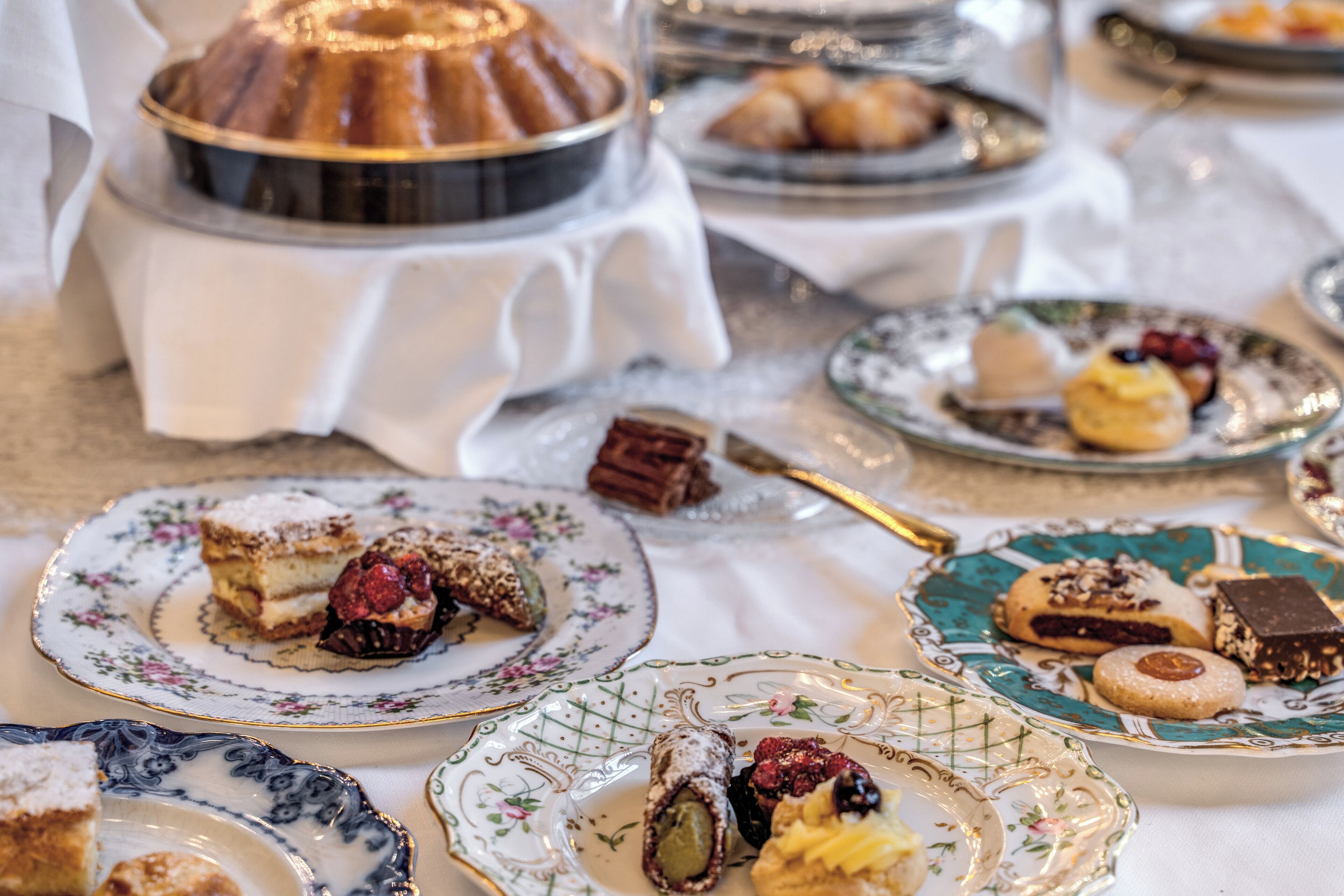 Une table où sont présentés divers desserts et pâtisseries, dont un gâteau en forme de couronne, sur des assiettes décorées.