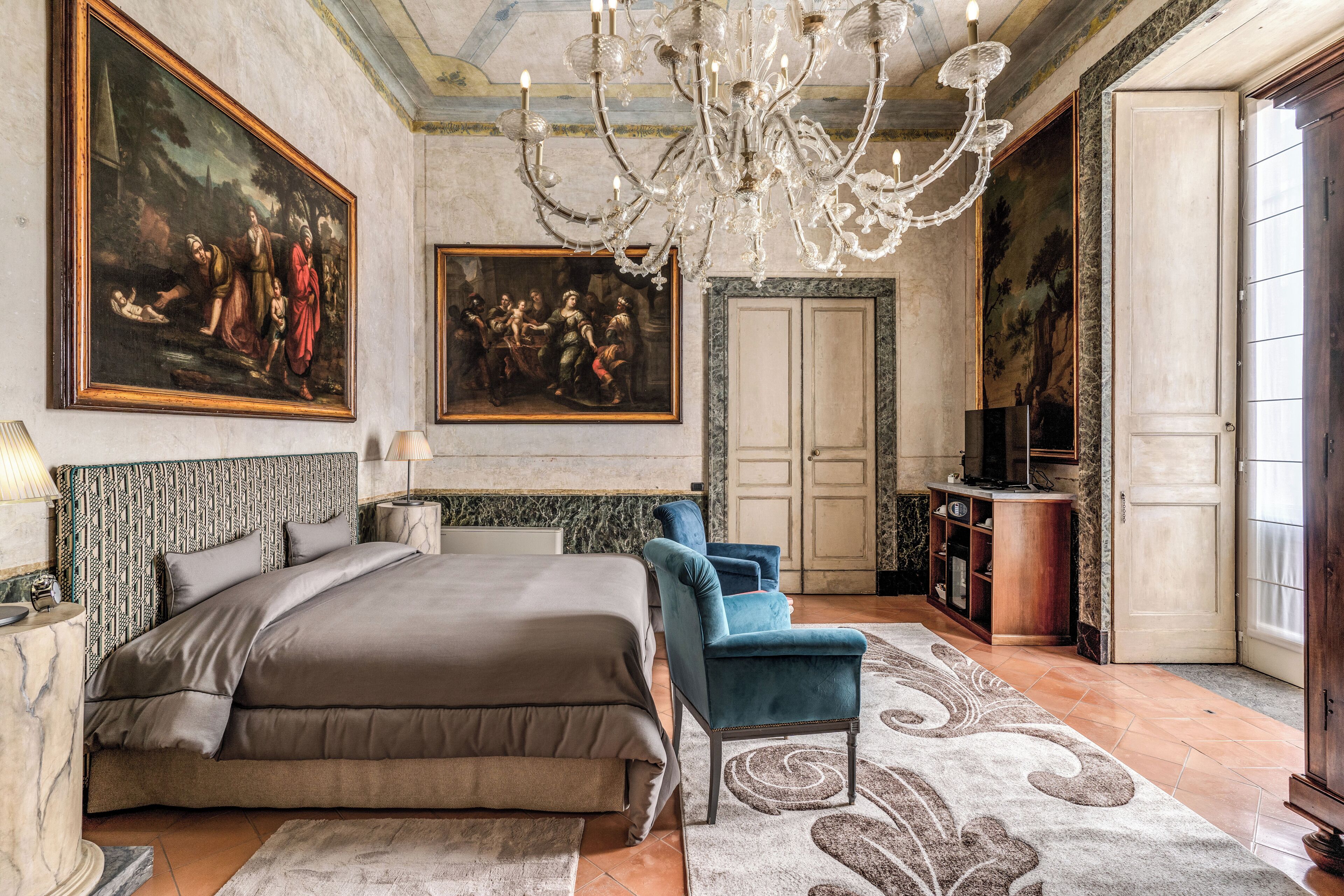 Une chambre à coucher avec un grand lit, un lustre et deux tableaux accrochés au mur.