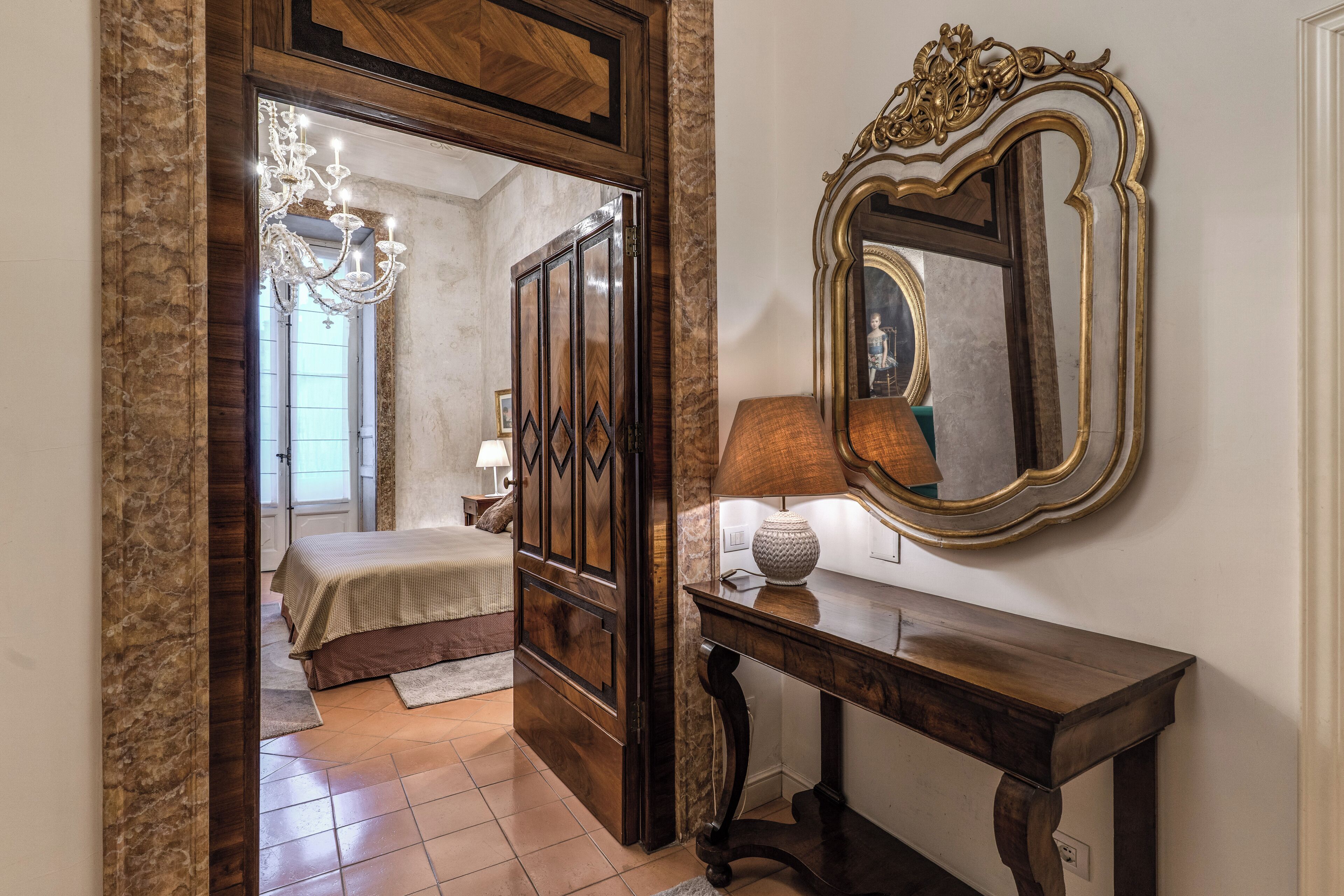 A bedroom with a bed, a dresser, a mirror, and a lamp.
