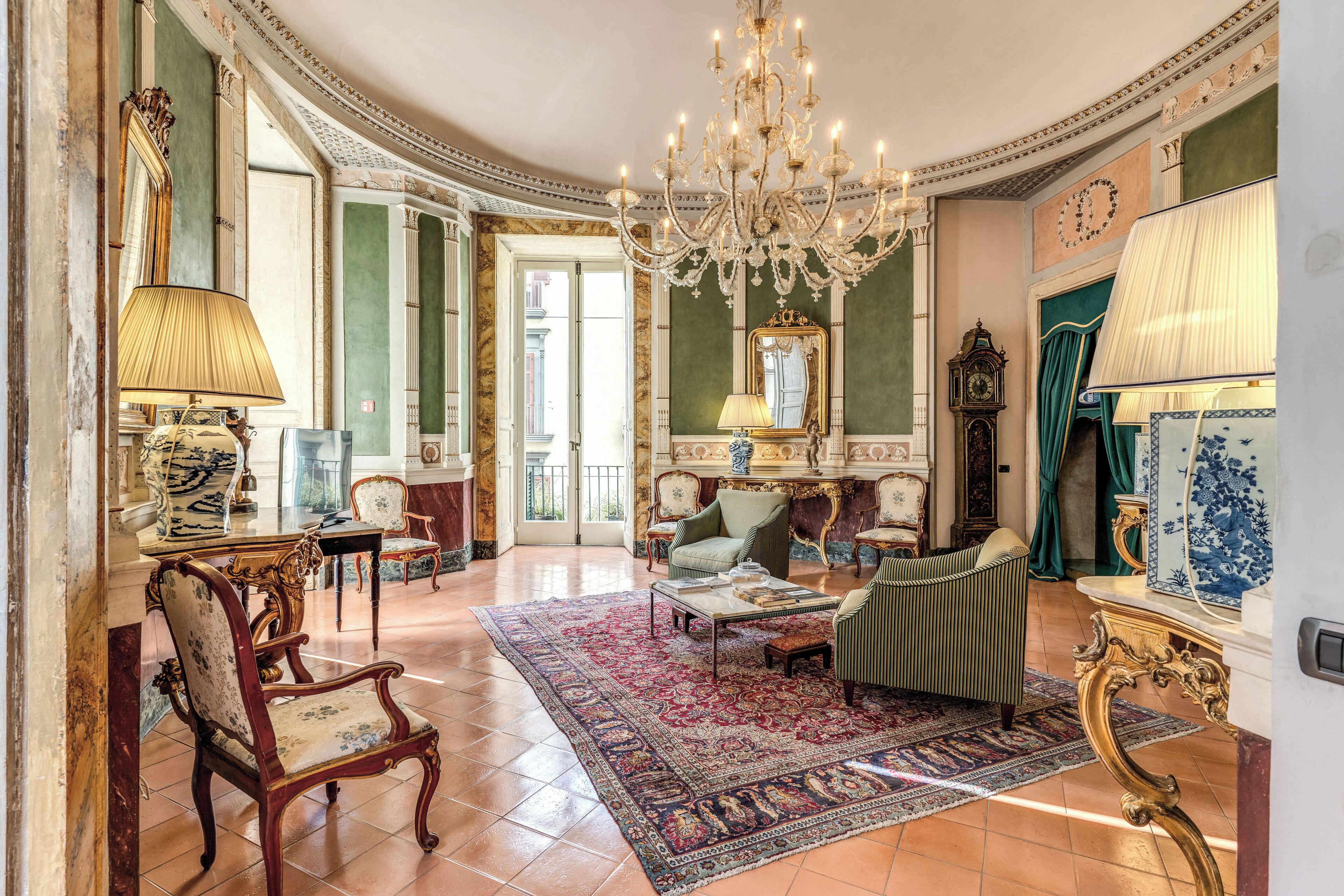 Una habitación amplia con candelabro, muebles antiguos y un espejo grande.