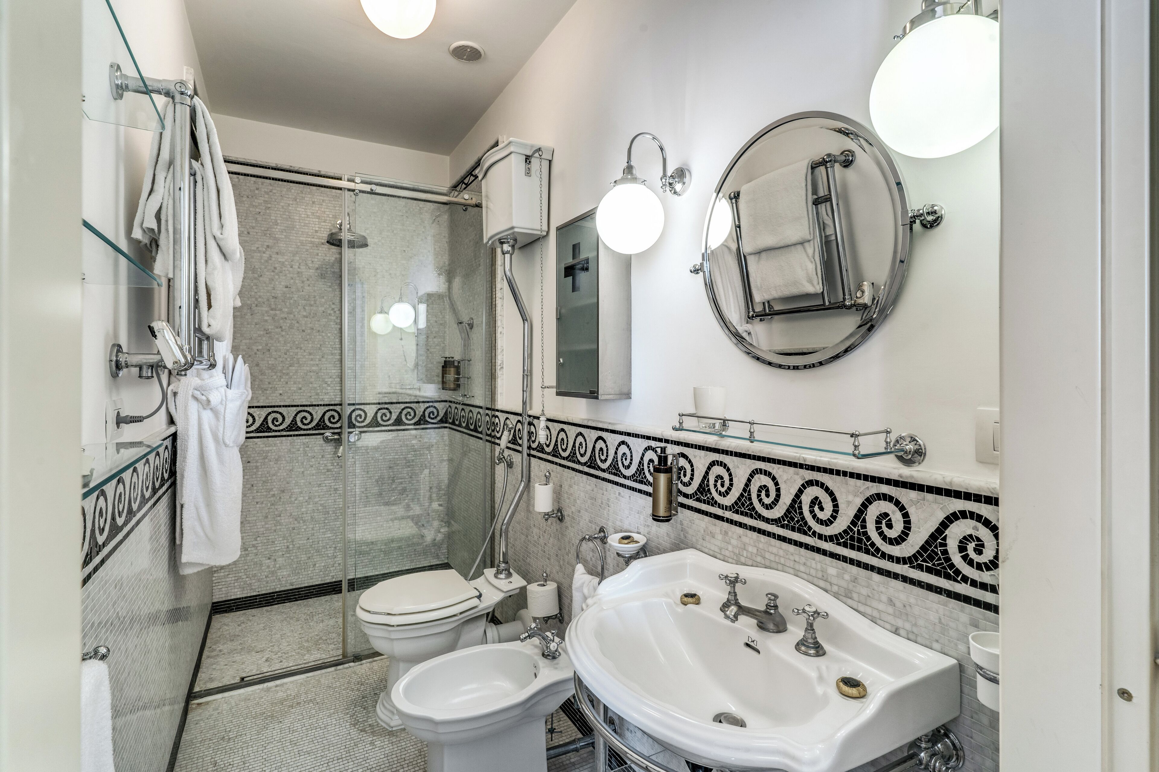 Un baño moderno con ducha de vidrio, lavamanos blanco y un inodoro.