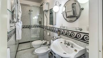 Un baño moderno con ducha de vidrio, lavamanos blanco y un inodoro.