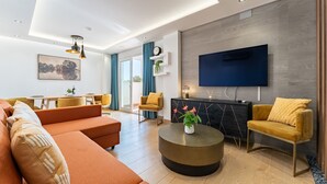 A modern living room with a sofa, chairs, a coffee table, and a TV mounted on the wall.