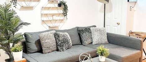 Una sala de estar moderna con un sofá gris, una mesa de centro blanca y plantas decorativas.