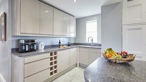 Una cocina moderna con armarios de tonos claros, una encimera de granito y un frutero.