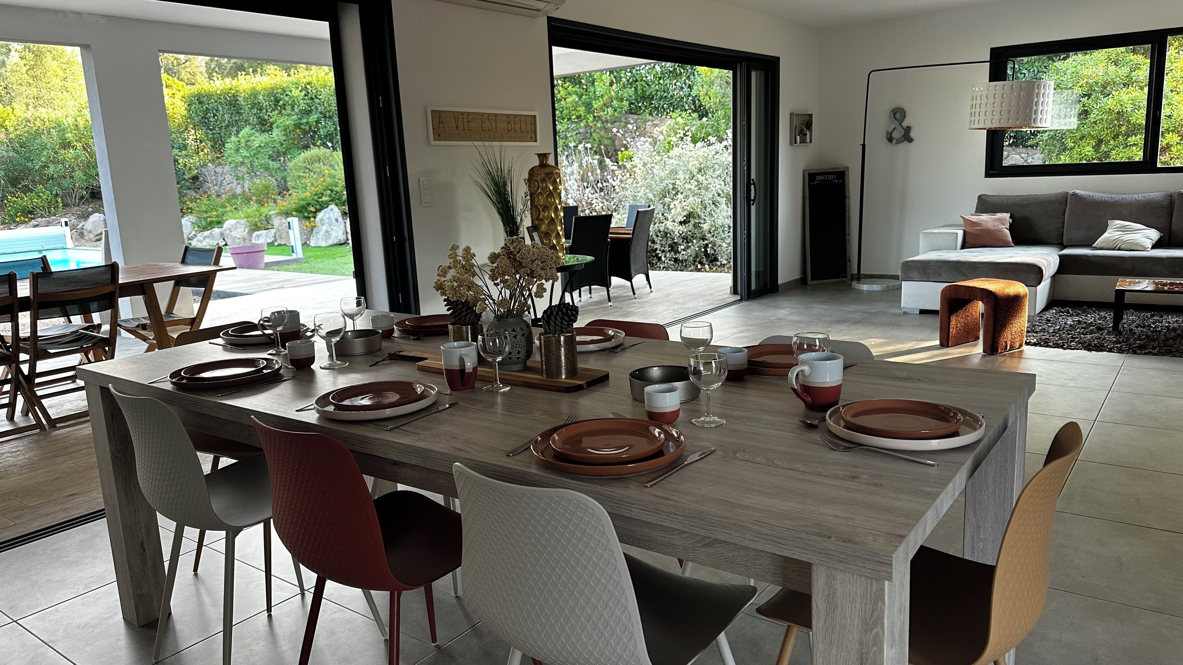 Un comedor moderno con una mesa de madera preparada para cuatro personas, rodeada de sillas.