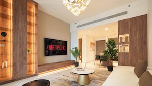 A modern living room with a flat-screen TV mounted on the wall, a round coffee table, and a sofa with cushions. - KeyRock - Palm View Luxury Stay in GB (Dubai)