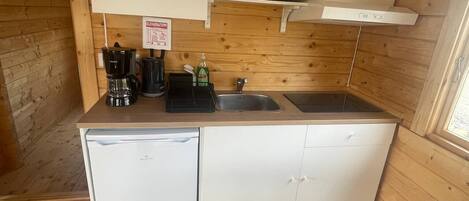 Et lille køkken med vask, kaffemaskine, blender og et minikøleskab.