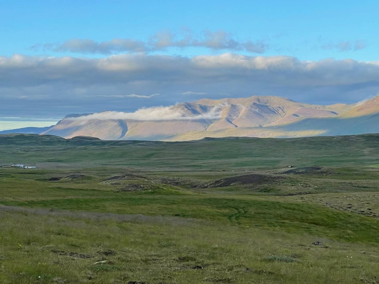 A vast, open landscape with rolling hills and a distant mountain range under a clear sky.