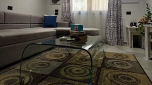 A living room with a sofa, a coffee table, a patterned rug, and a ceiling light fixture. - Level One Living , Morden comfort in a prime location compound feels like Home (Hurghada)