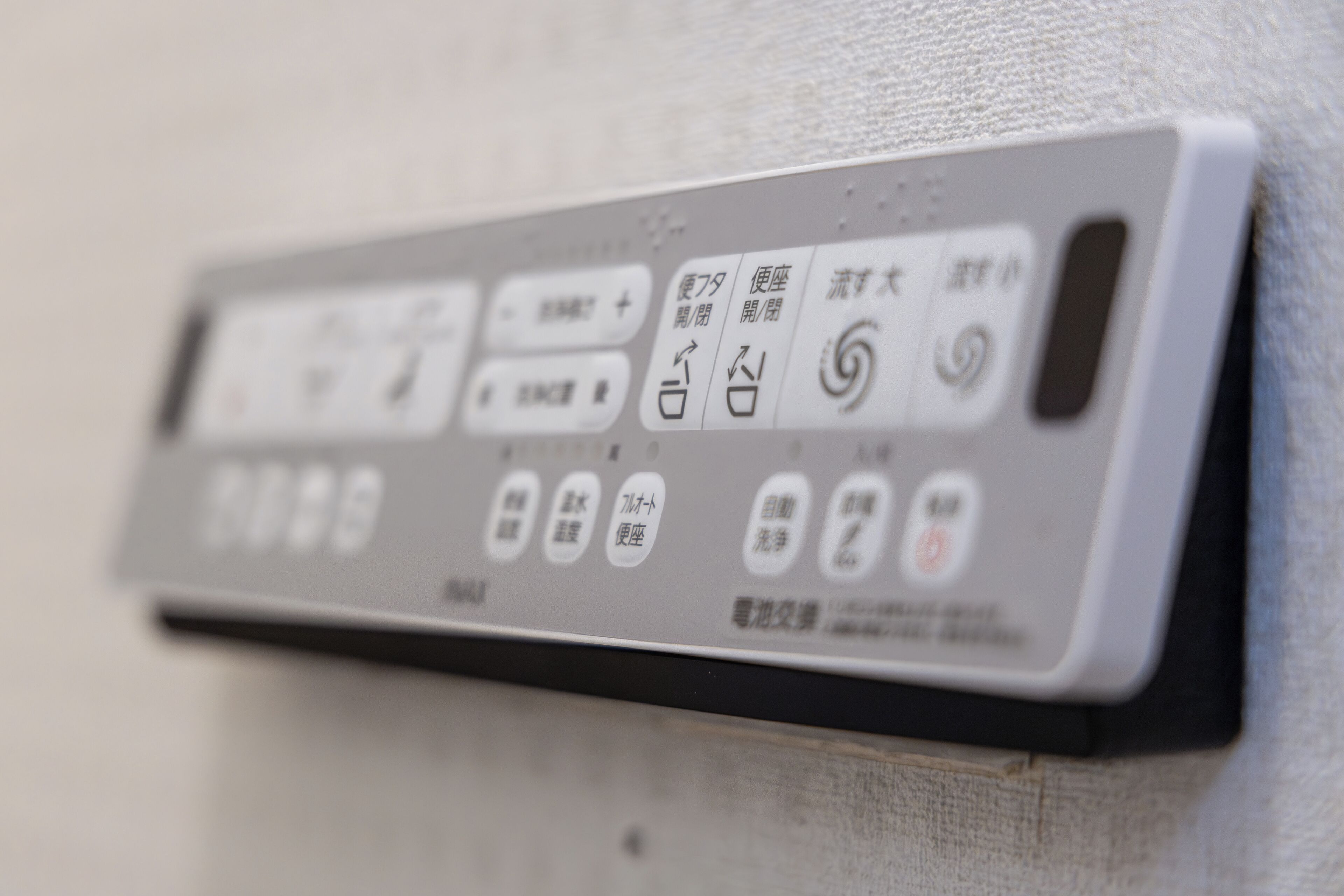 A close-up of a remote control with Japanese buttons.