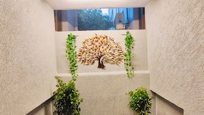 A narrow corridor with a textured wall, a ceiling light, and two potted plants on either side.