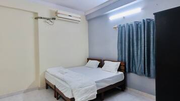 Une chambre à coucher comprenant un lit, un ventilateur de plafond, un appareil de climatisation, un rideau et une étagère fixée au mur.