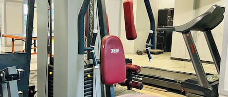 Una palestra con attrezzature per esercizi, tapis roulant e uno specchio.
