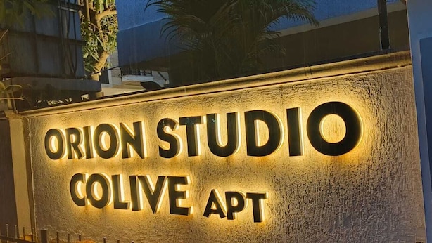 A sign for Orion Studio Colive Apt with illuminated letters.