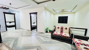 A spacious room with a patterned marble floor, a sofa with a decorative throw, a ceiling fan, and a bed in the background.