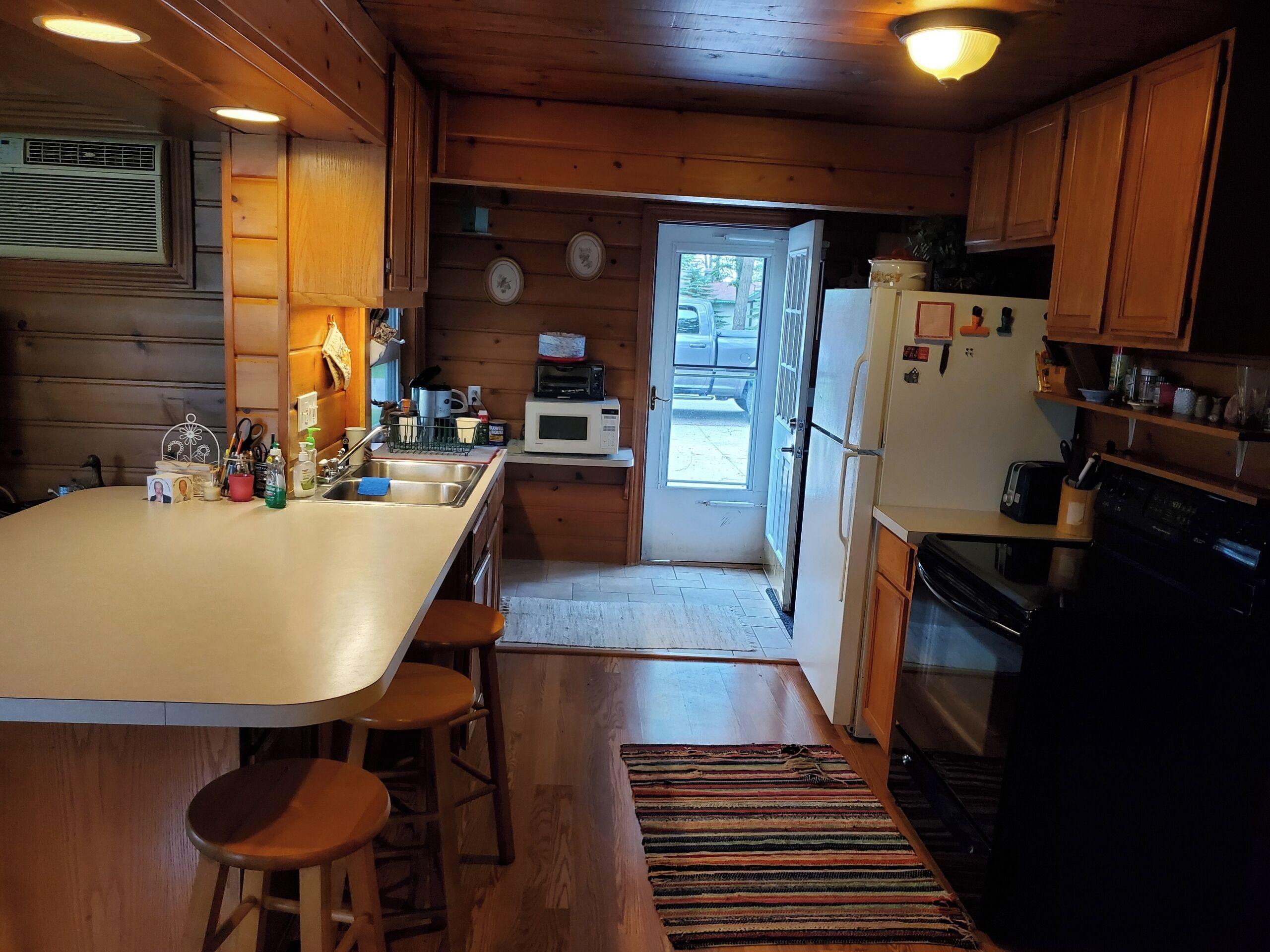 Une cuisine avec des meubles de rangement en bois, un réfrigérateur, un four à micro-ondes et un évier.