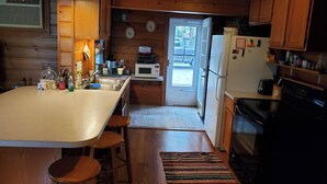 A kitchen with wooden cabinets, a refrigerator, a microwave, and a sink. - Fabulous 2-bedroom Otsego lake cottage in charming Gaylord (Gaylord)