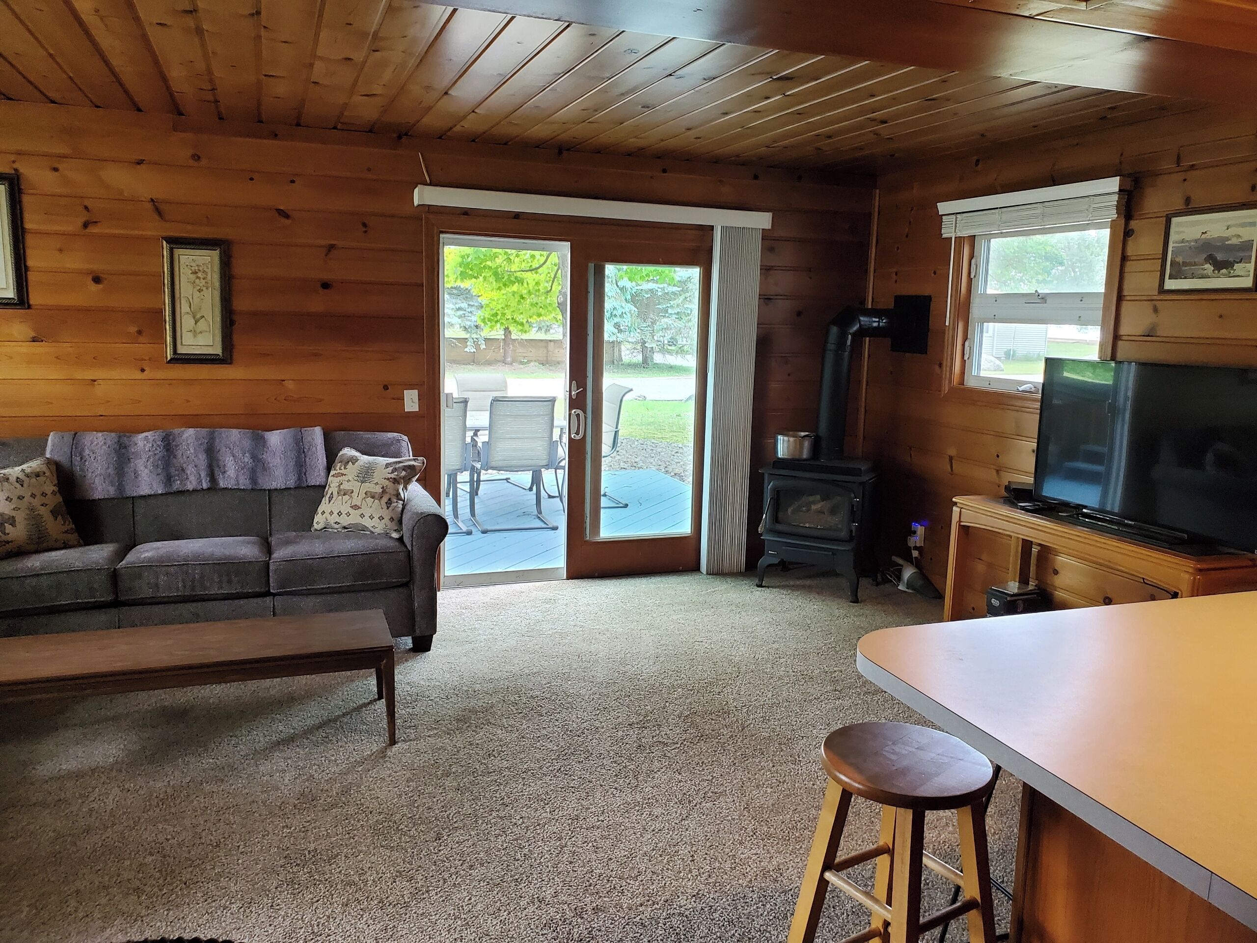 L’intérieur chaleureux d’un chalet avec un canapé, un téléviseur, une table en bois et une cheminée.