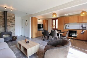 Et moderne køkken med træskabe, et spiseområde med bord og stole, en sofa og en pejs.