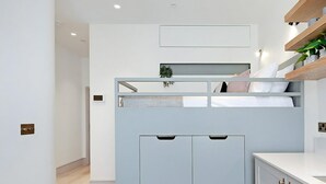 A compact room with a bunk bed, a kitchenette, and a small seating area. - The Mezzanine Studio at Bramham (London)